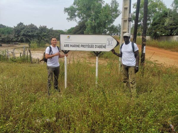 Photo of Quentin Lematais and Clement Sambou in front of the Sign of the Marine Protected Area of Abéné